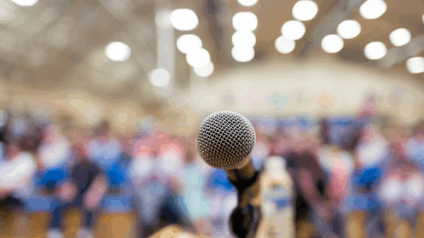 A microphone in front of a seated crowd