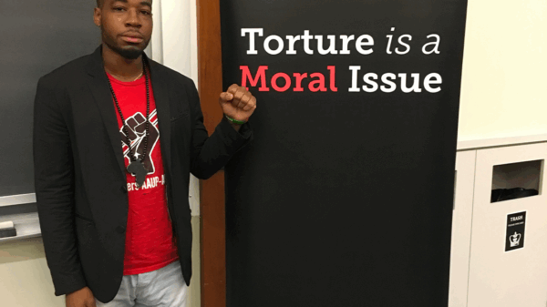 Mark Hopkins, a survivor of solitary confinement, stands next to the words "Torture is a Moral Issue."