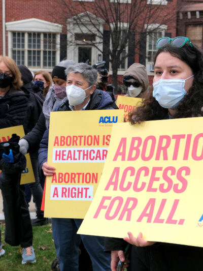 A group of masked protesters are holding signs that read: "Abortion access for all" and "Abortion is healthcare. Abortion is a right."