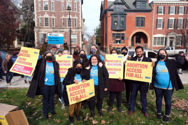 A group of people are standing with signs that read "abortion access for all" and "real police reform now"