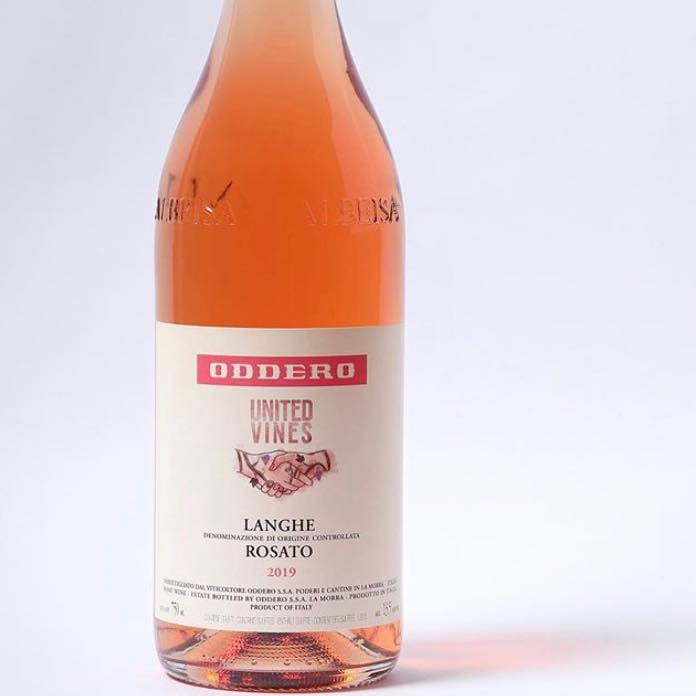 A glass bottle containing pink wine is displayed against a white background. It reads