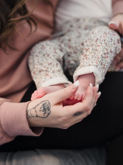 a woman cradles a baby in her arms, touching the baby's feet