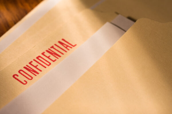 A manila folder with a bright red "confidential" stamp is laid out on a table.