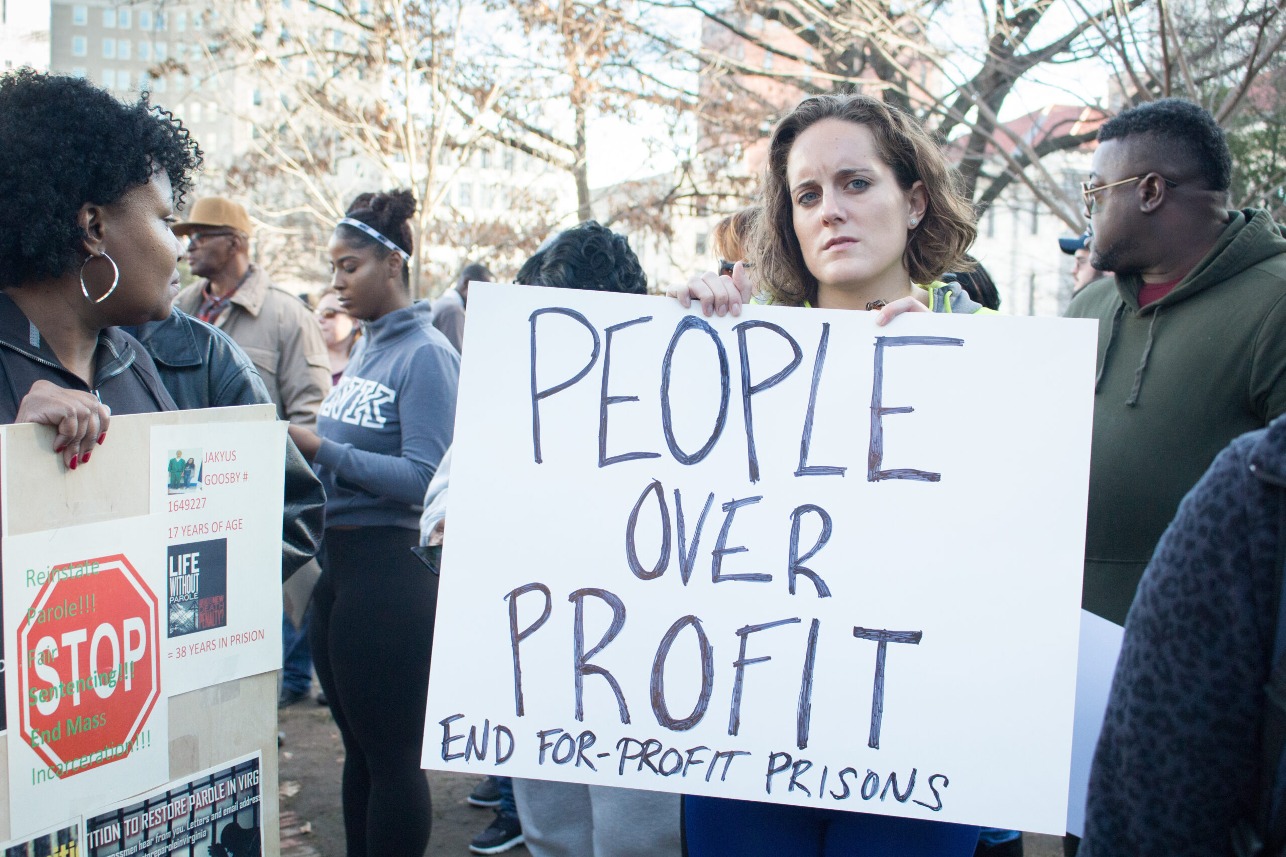 white woman holding a protest sign reading