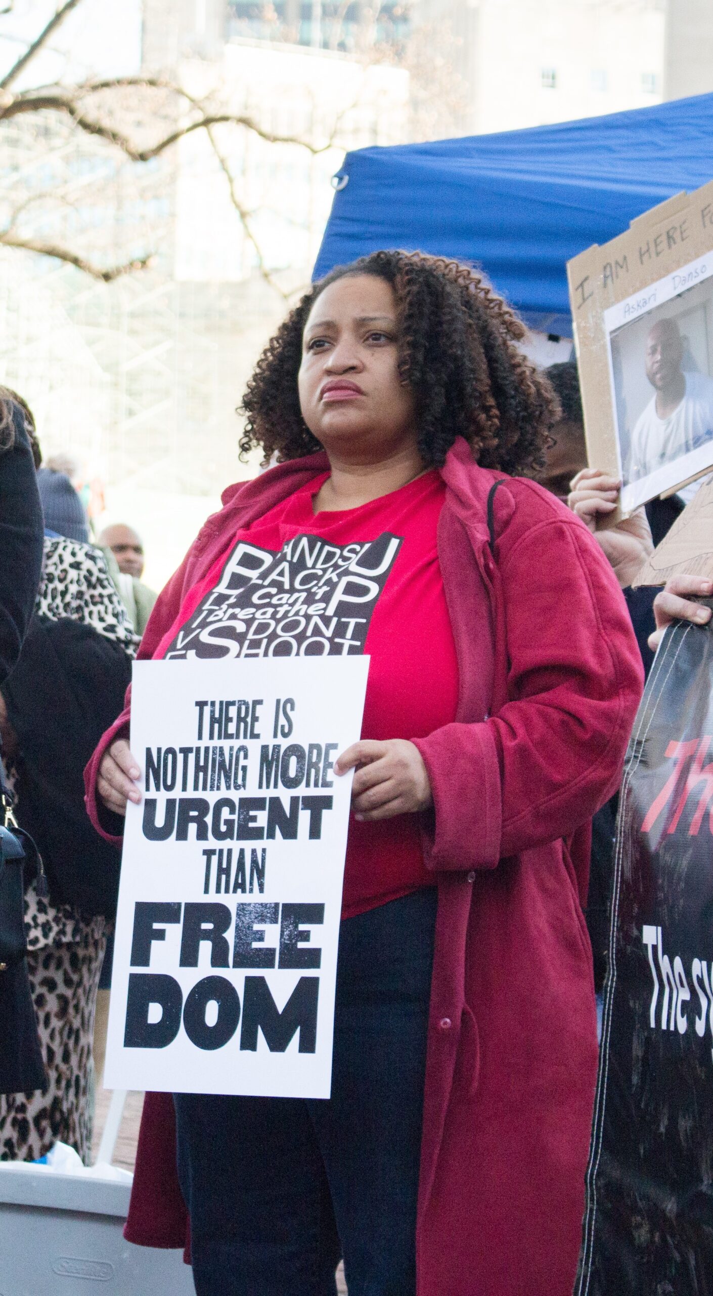 Black woman holding sign amidst protest reading
