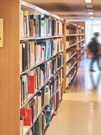 School library shelves with a blurred image of a person walking