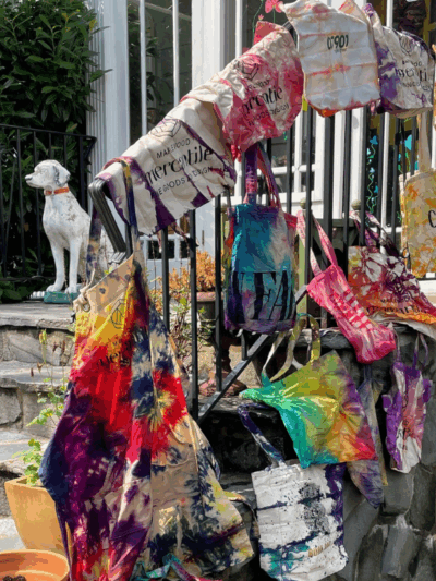 tie dye bags hanging over a railing in front of a white house