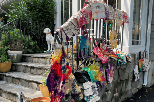tie dye bags hanging over a railing in front of a white house