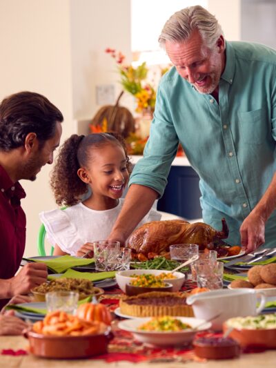 Mult-racial family enjoying thanksgiving dinner around a table