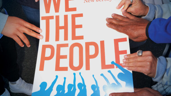 Hands holding a sign that reads "We The People," with an ACLU-NJ logo and the words 2023 Annual Report