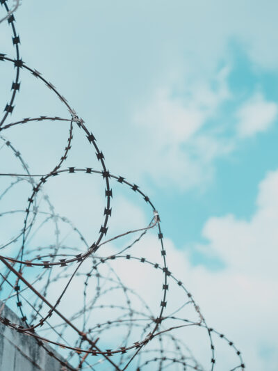 Barbed wire with blue sky and clouds in background