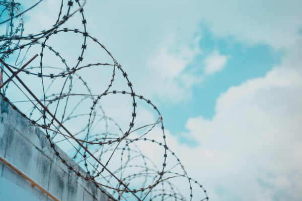 Barbed wire with blue sky and clouds in background