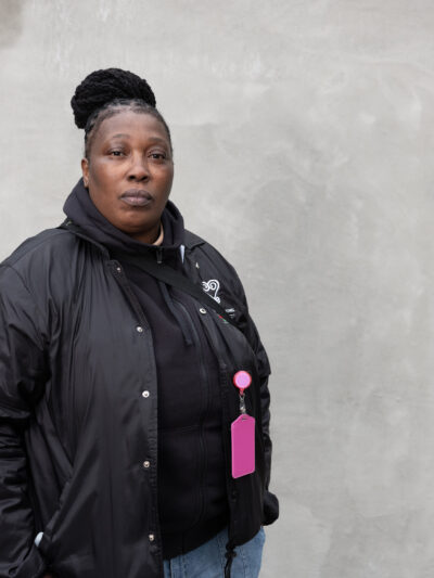 Black women wearing a black jacket in front of a grey background