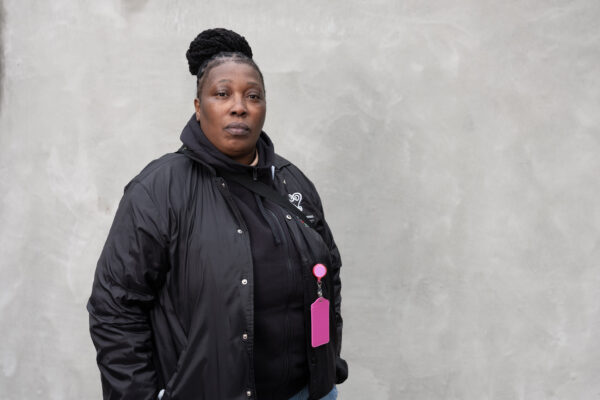 Black women wearing a black jacket in front of a grey background