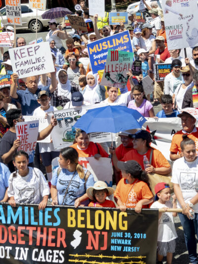 Group of protesters marching with banner reading "Families Belong Together. Not in Cages."