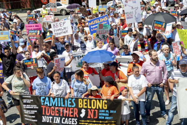 Group of protesters marching with banner reading "Families Belong Together. Not in Cages."