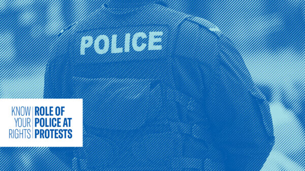 Single police officer standing and monitoring a crowd