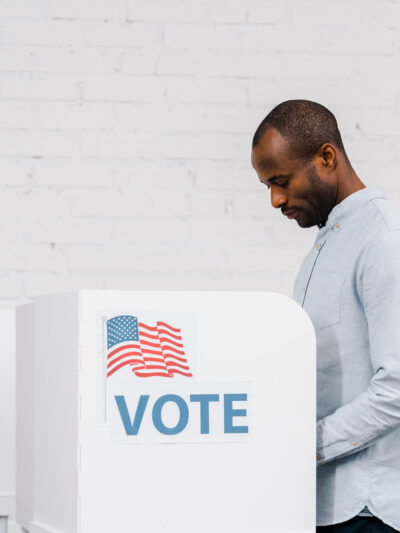 Black Man voting on white brick background