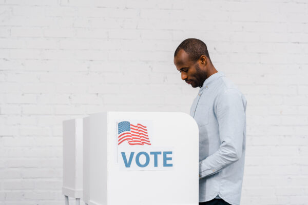 Black Man voting on white brick background