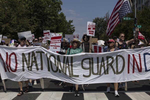 Demonstrators march in Washington, DC carrying a banner that reads " NO NATIONAL GUARD IN DC".