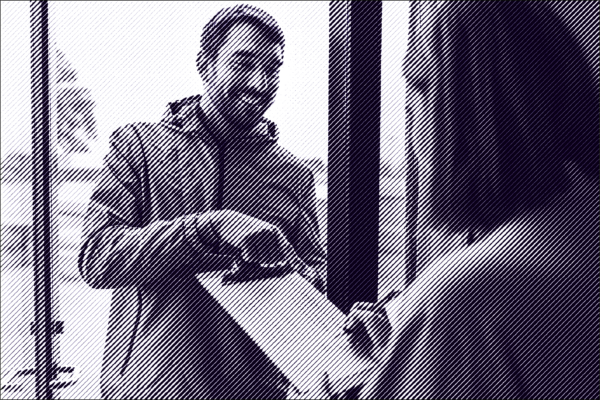 Man with brown hair and a beard holds a clipboard in front of a woman with medium length brown hair.