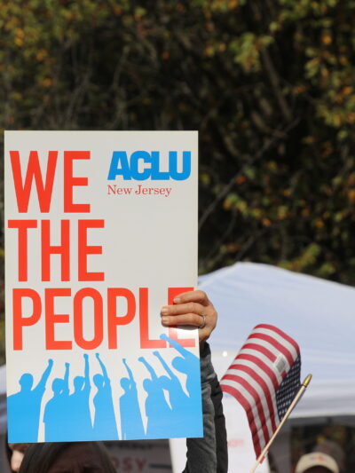 a protest sign reading "we the people" with the ACLU of New Jersey logo