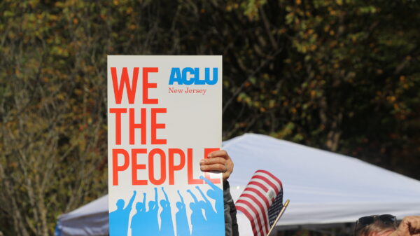 a protest sign reading "we the people" with the ACLU of New Jersey logo