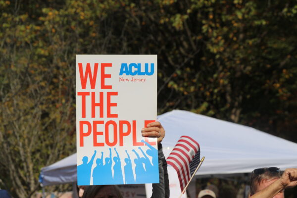 a protest sign reading "we the people" with the ACLU of New Jersey logo