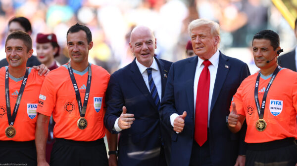 FIFA President Gianni Infantino and President Donald Trump pose with FIFA officials in bright orange referee jerseys and medals during the awards ceremony after Chelsea defeated Paris Saint-Germain 3–0 in the 2025 FIFA Club World Cup final at MetLife Stadium in East Rutherford, New Jersey.