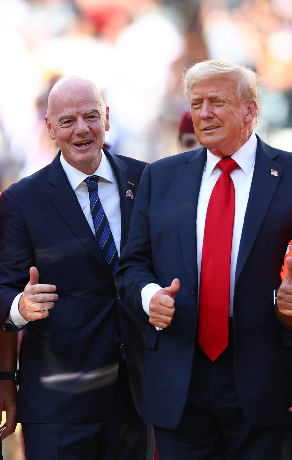 FIFA President Gianni Infantino and President Donald Trump pose with FIFA officials in bright orange referee jerseys and medals during the awards ceremony after Chelsea defeated Paris Saint-Germain 3–0 in the 2025 FIFA Club World Cup final at MetLife Stadium in East Rutherford, New Jersey.