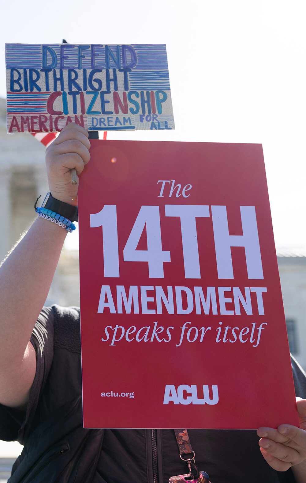 A demonstrator holding signs advocating for the 14th Amendment at the U.S. Supreme Court in Washington, D.C. for the birthright citizenship case Trump v. Barbara.