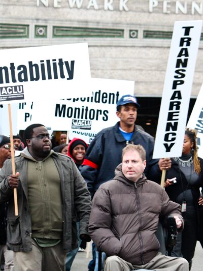 A group of protestors holding signs with "accountability" and "Transparency" in Newark, NJ.