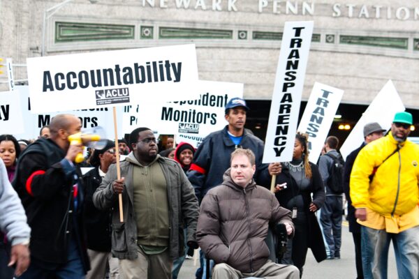 A group of protestors holding signs with "accountability" and "Transparency" in Newark, NJ.