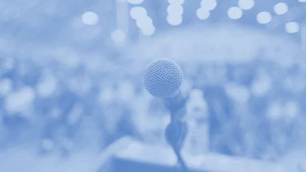 A mircophone on a podium with a crowd of people in the background with a blue strip treatment