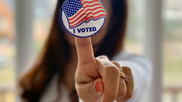 A woman holds up an "I voted" sticker