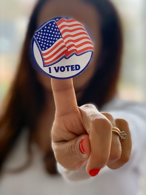 A woman holds up an "I voted" sticker