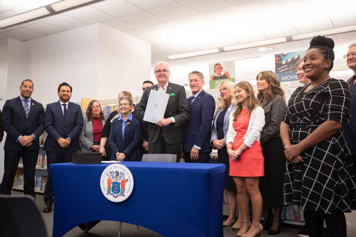 Governor Phil Murphy poses with a crowd after signing the Freedom to Read Act