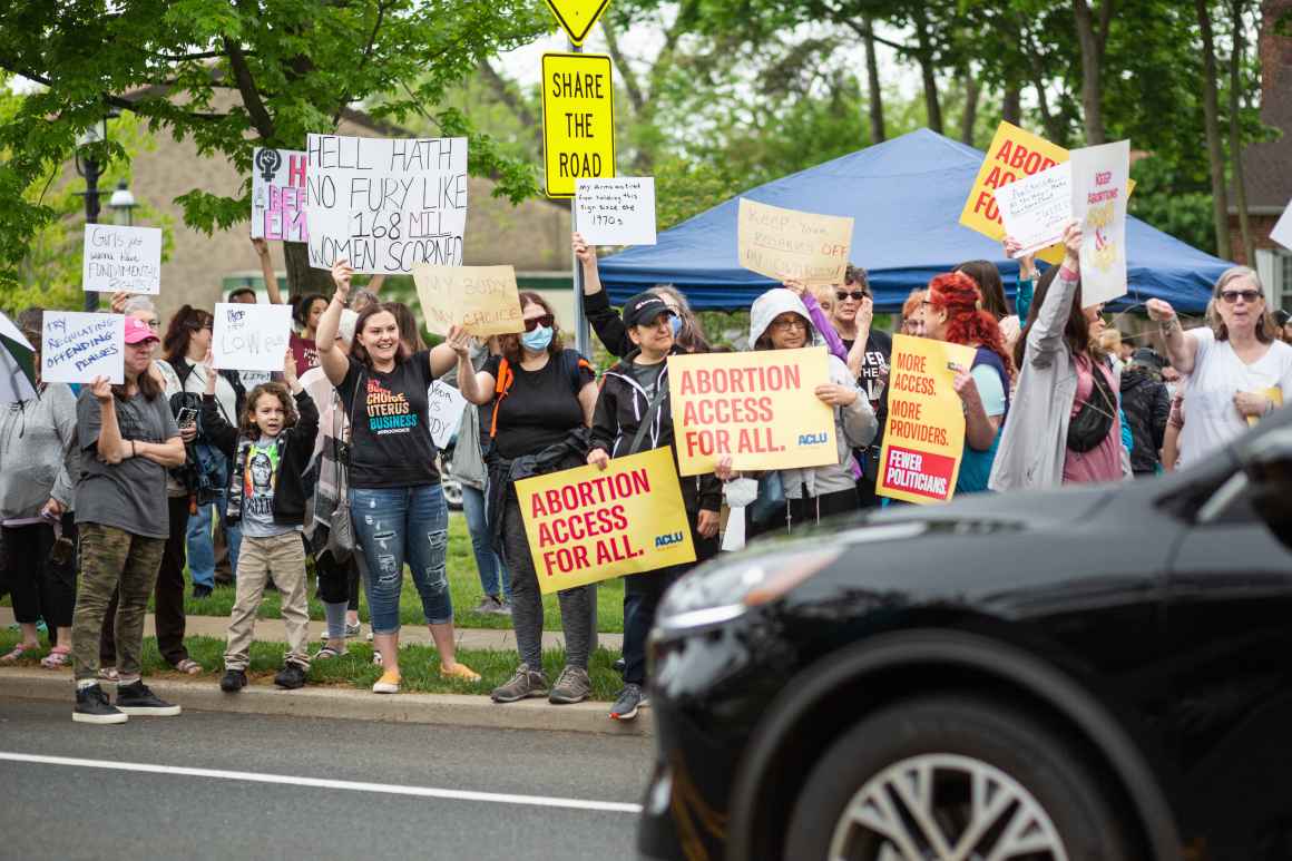 Crowd protesting with signs reading "Abortion Access For All"