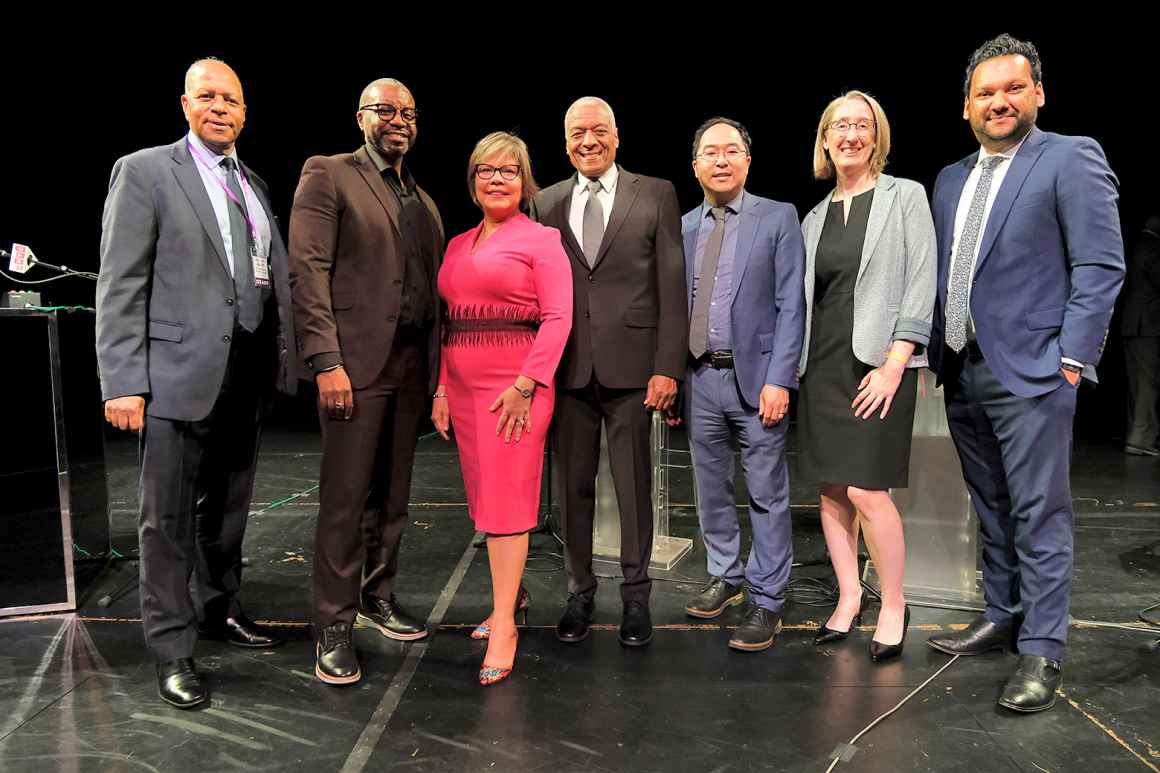 A group of people pose on a stage after a debate