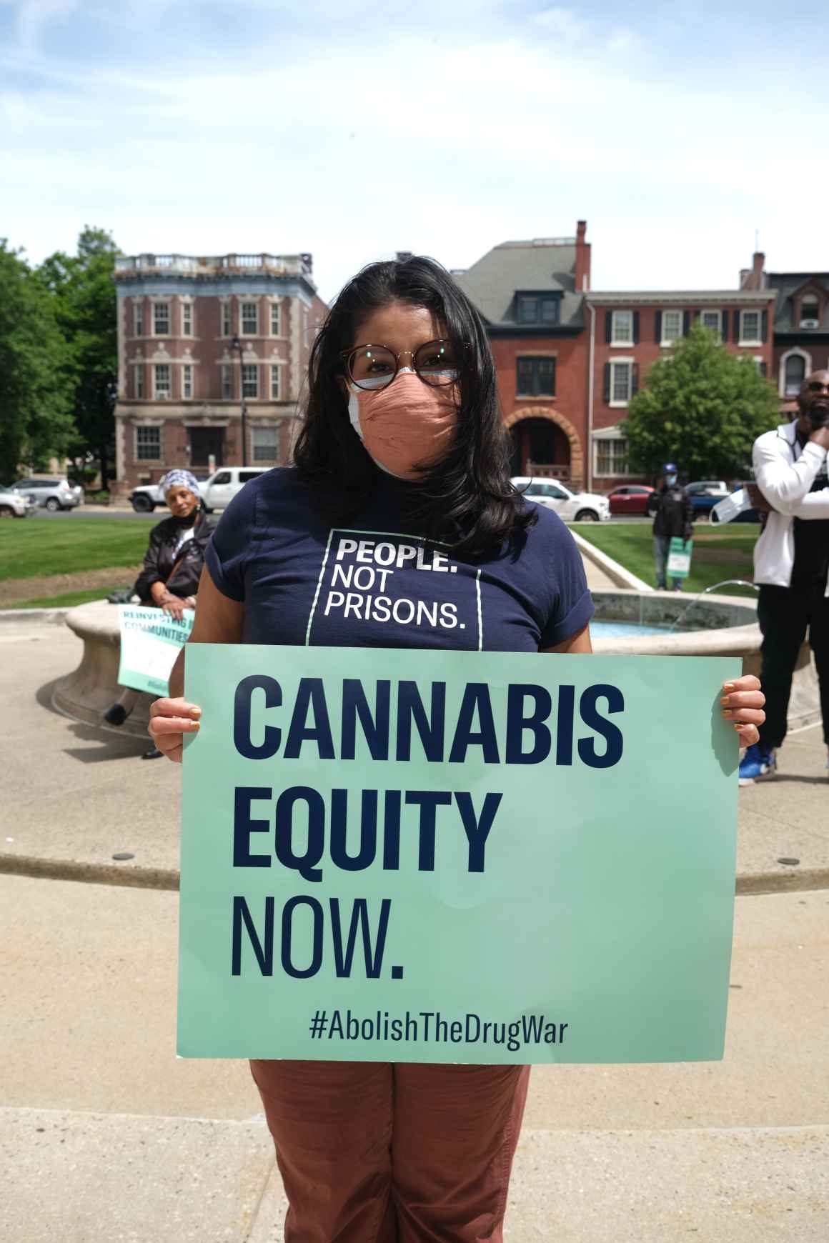 Woman holding sign that says "Cannabis Equity Now"