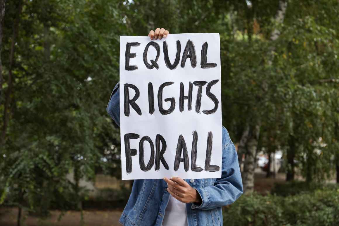 Hands holding a sign that reads "EQUAL RIGHTS FOR ALL"