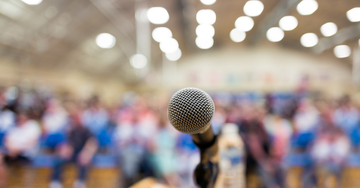 A microphone in front of a seated crowd