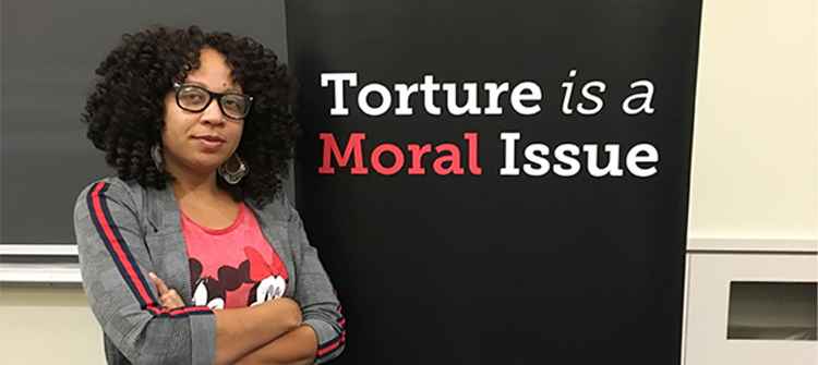 Solitary confinement survivor Nafeesah Goldsmith stands next to the words "torture is a moral issue."