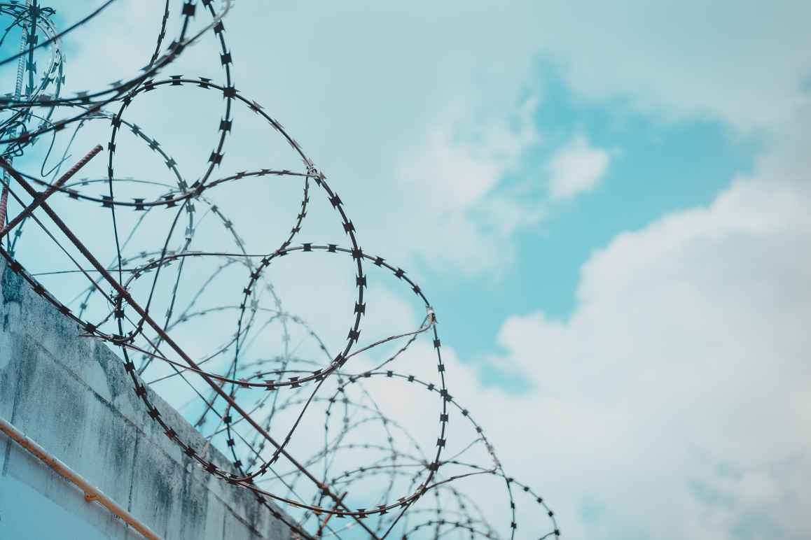 Barbed wire with blue sky and clouds in background