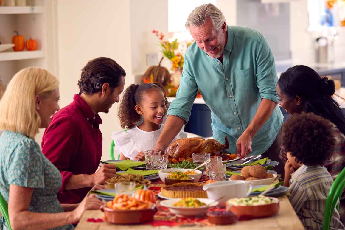 Mult-racial family enjoying thanksgiving dinner around a table
