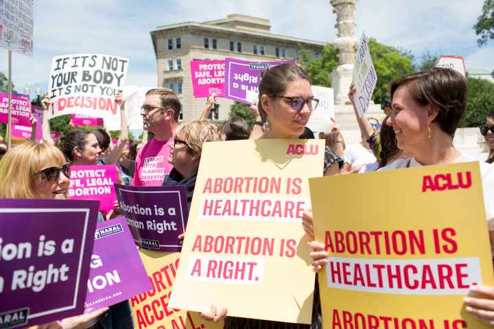 Protestors holding signs reading "abortion is healthcare. Abortion is a right"