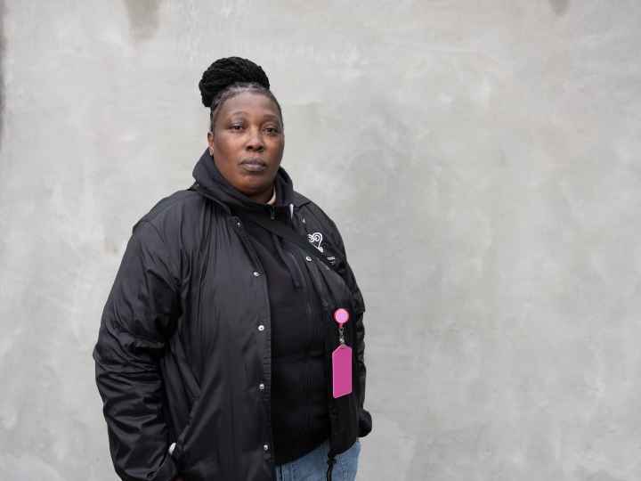 Black women wearing a black jacket in front of a grey background