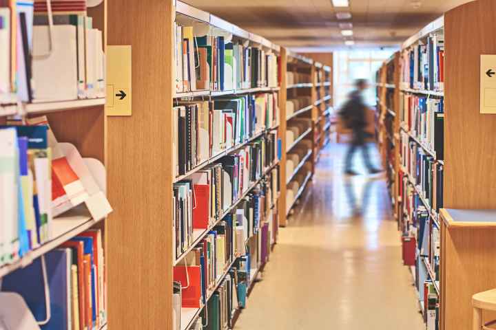 School library shelves with a blurred image of a person walking