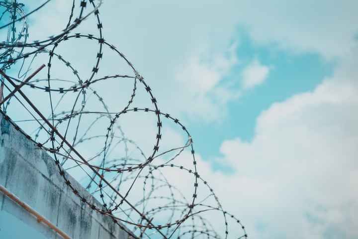 Barbed wire with blue sky and clouds in background
