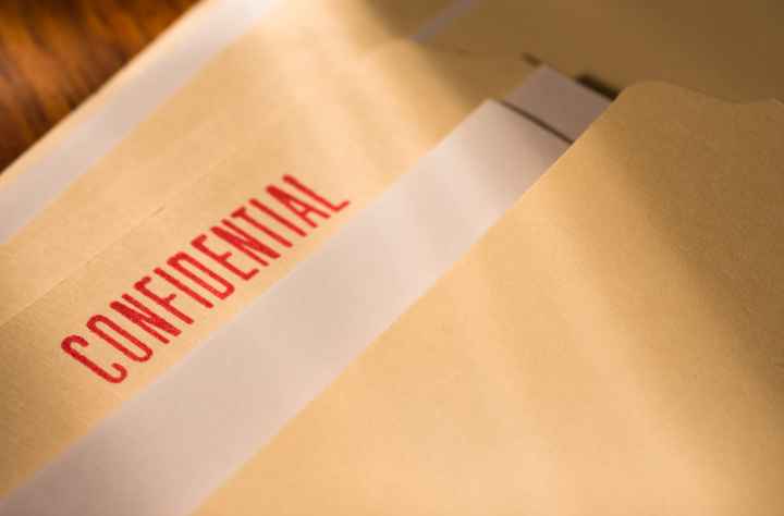 A manila folder with a bright red "confidential" stamp is laid out on a table.